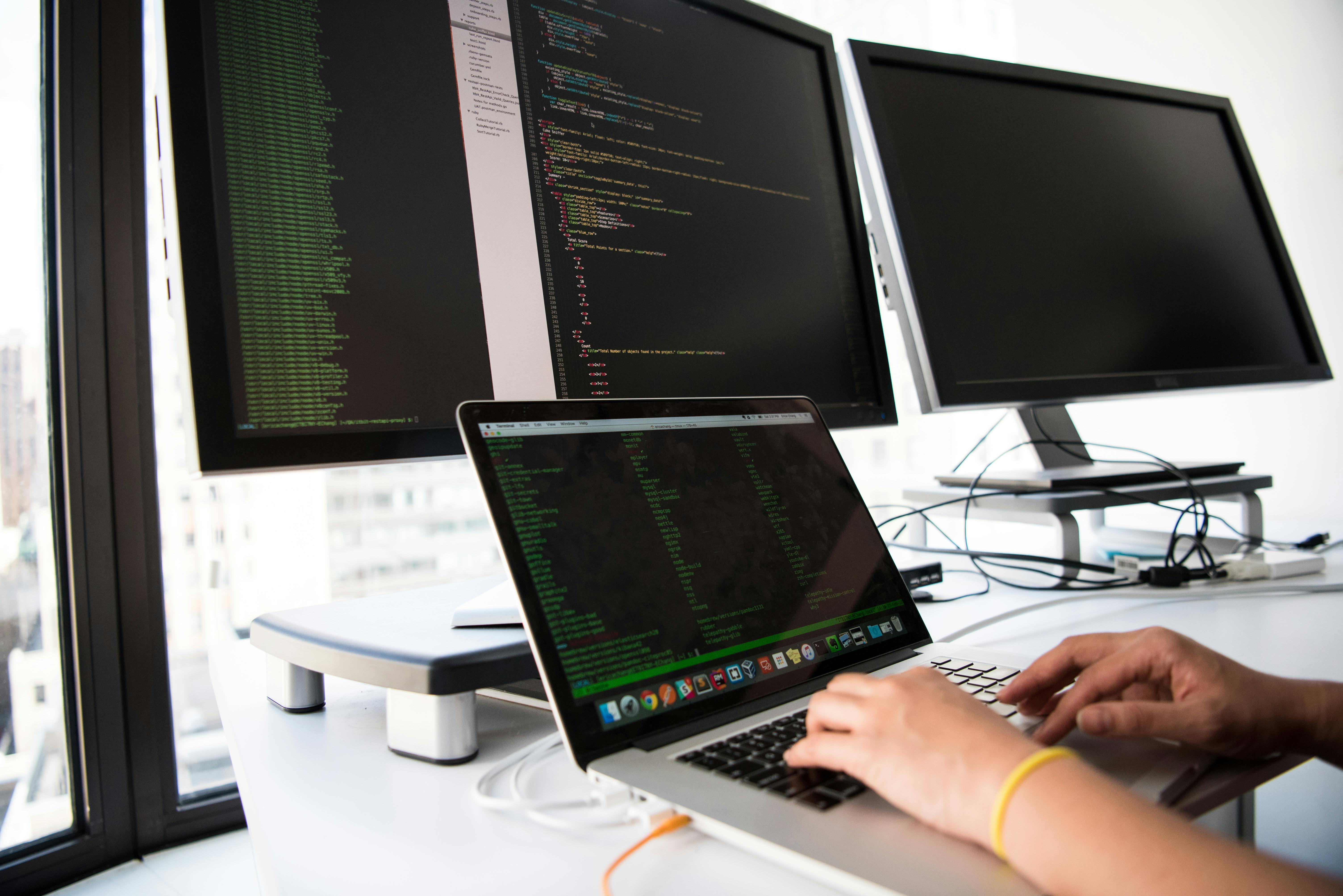 Programmer analyzing website performance metrics on dual monitors